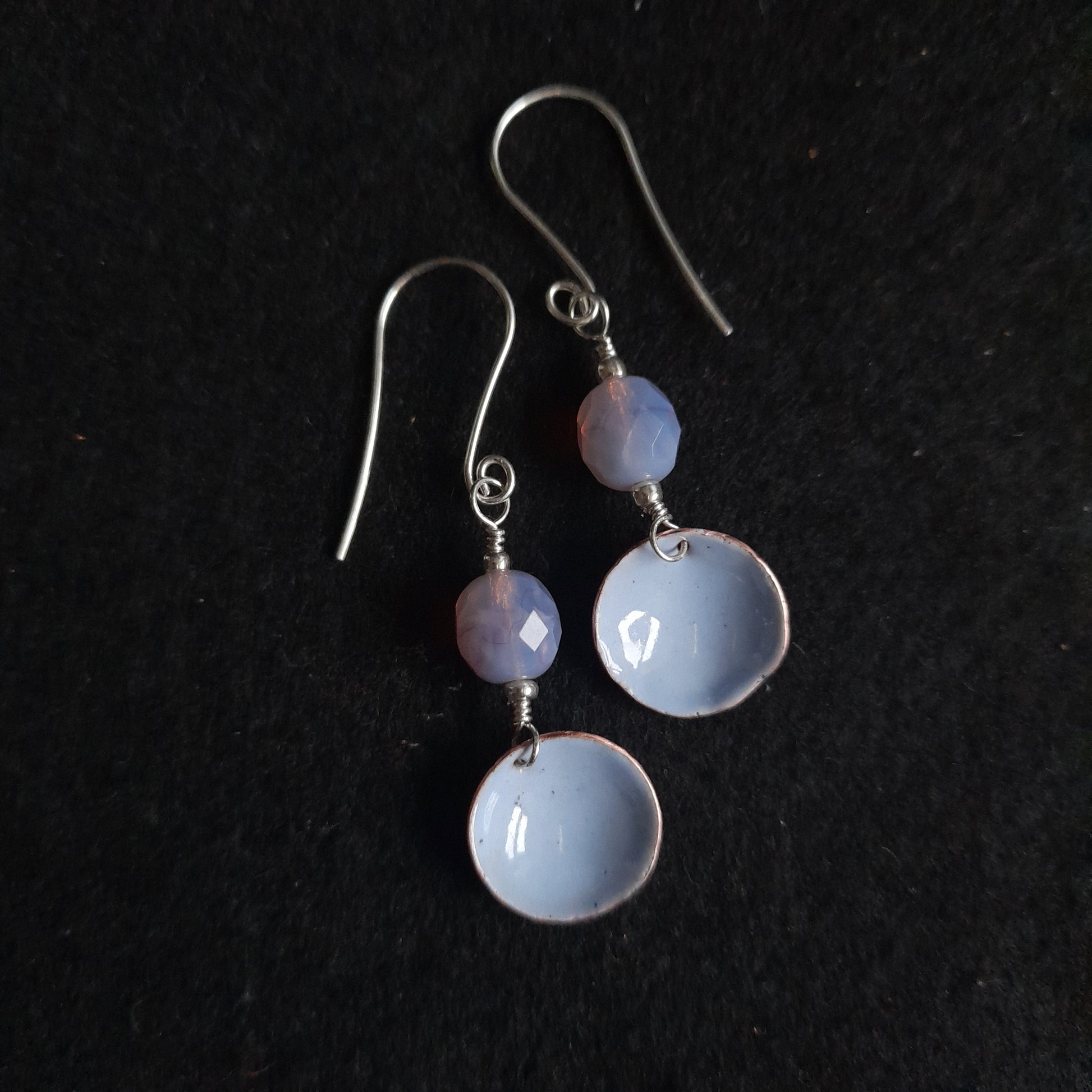 A pair of handmade pale lavender blue enamel bowl dangle earrings, presented with a faceted mauve glass bead, dangle earrings on silver earwires.