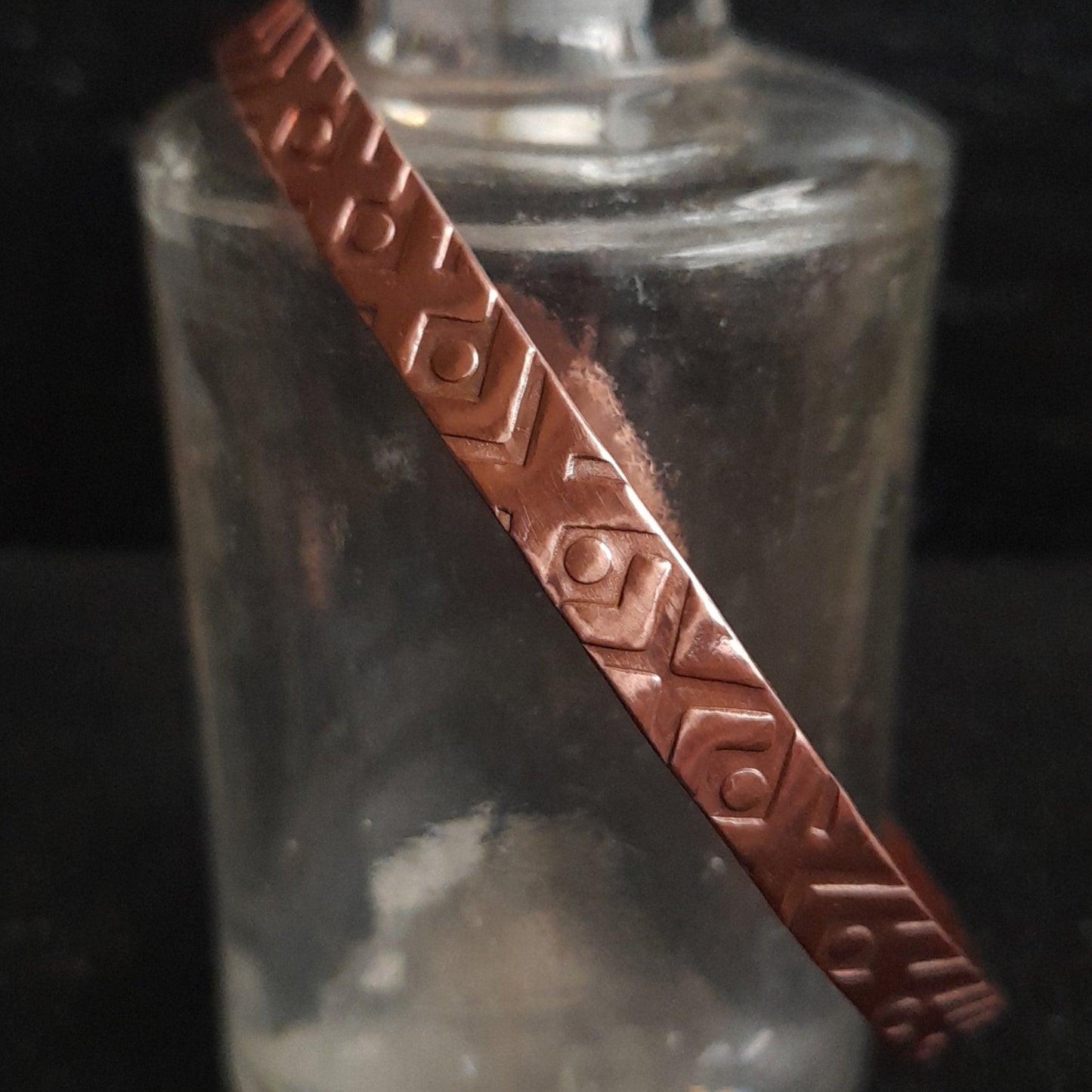 Diagonal view of geometric patterned copper bangle 