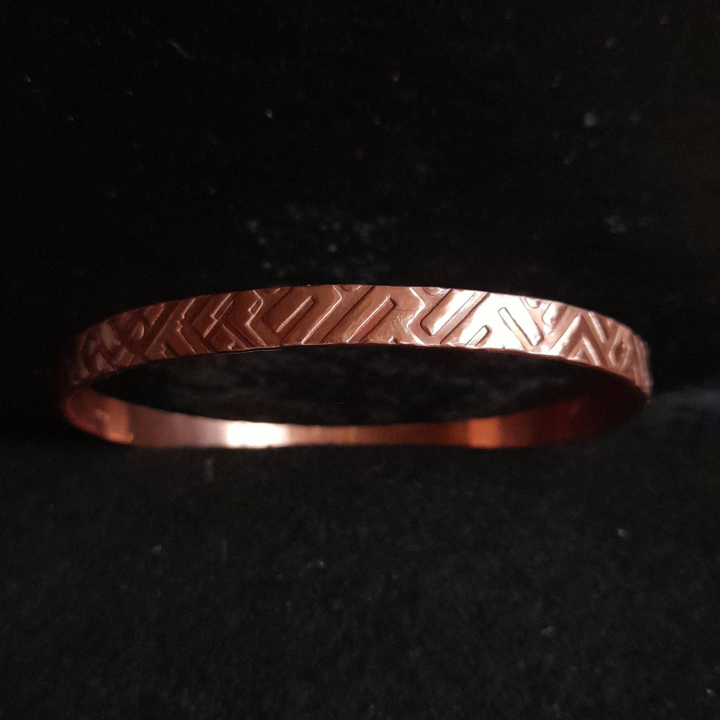 copper bangle showing geometric embossed design