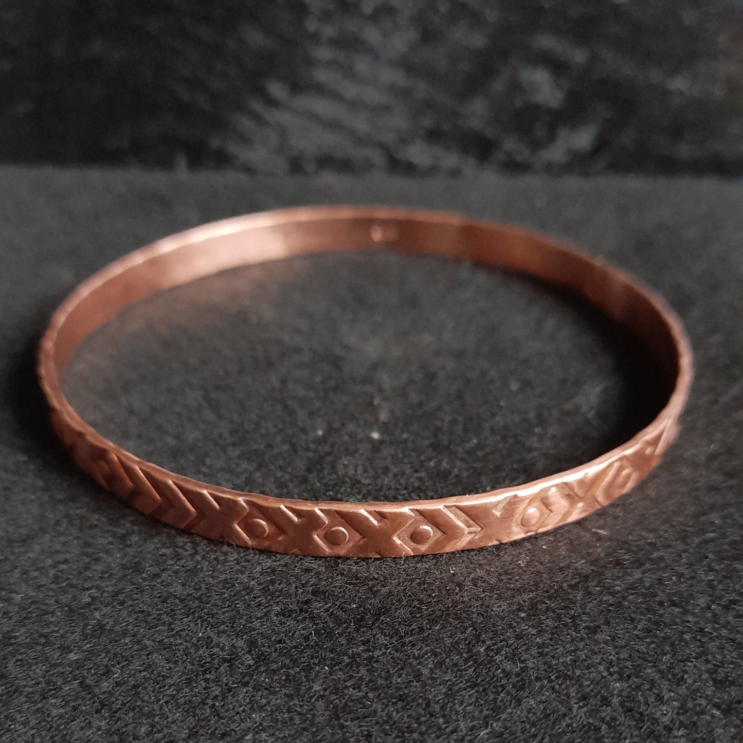 Textured copper soldered bangle on black background