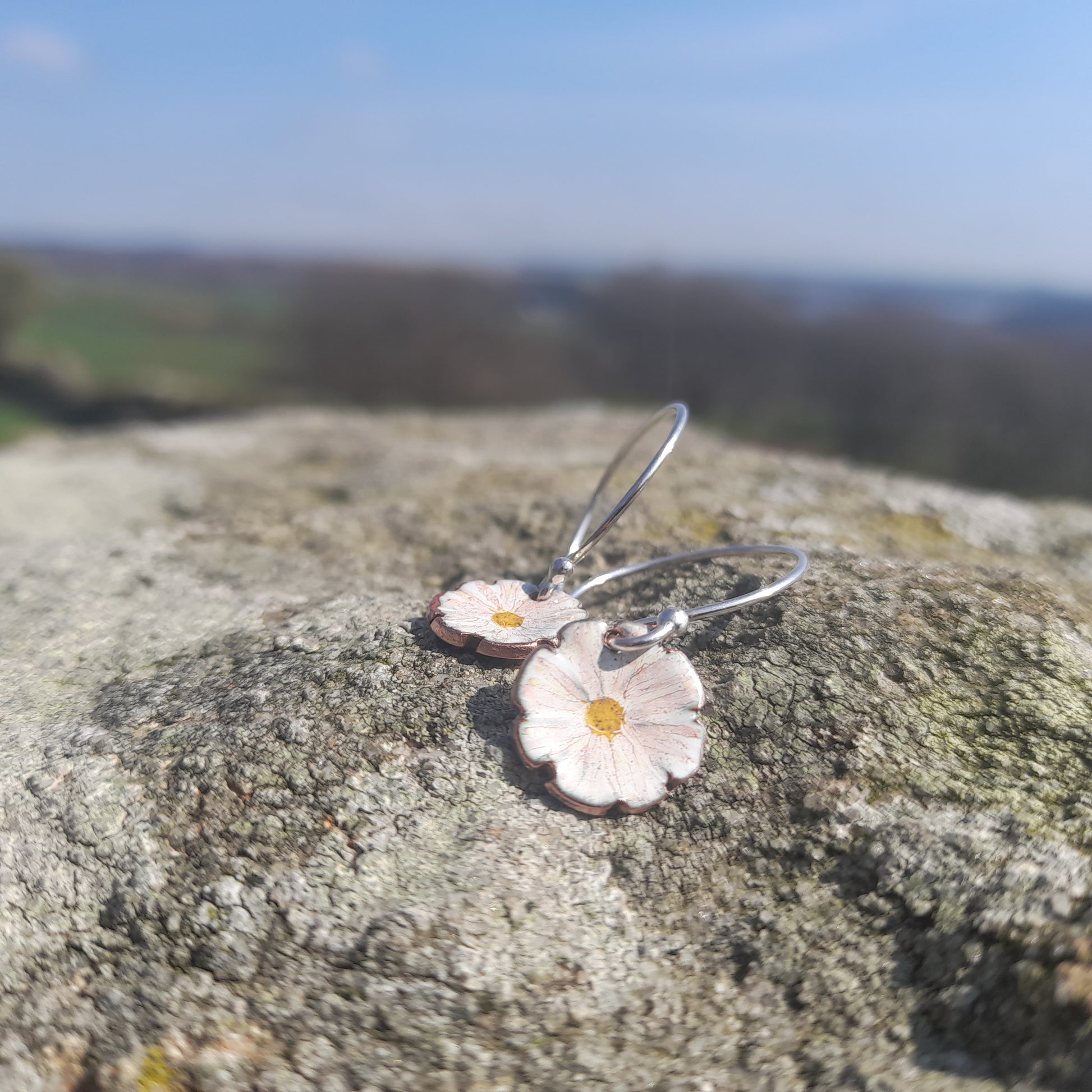 fluted white daisy like flower earring, with delicate handpainted detail and yellow centre. on silver ear wires. 